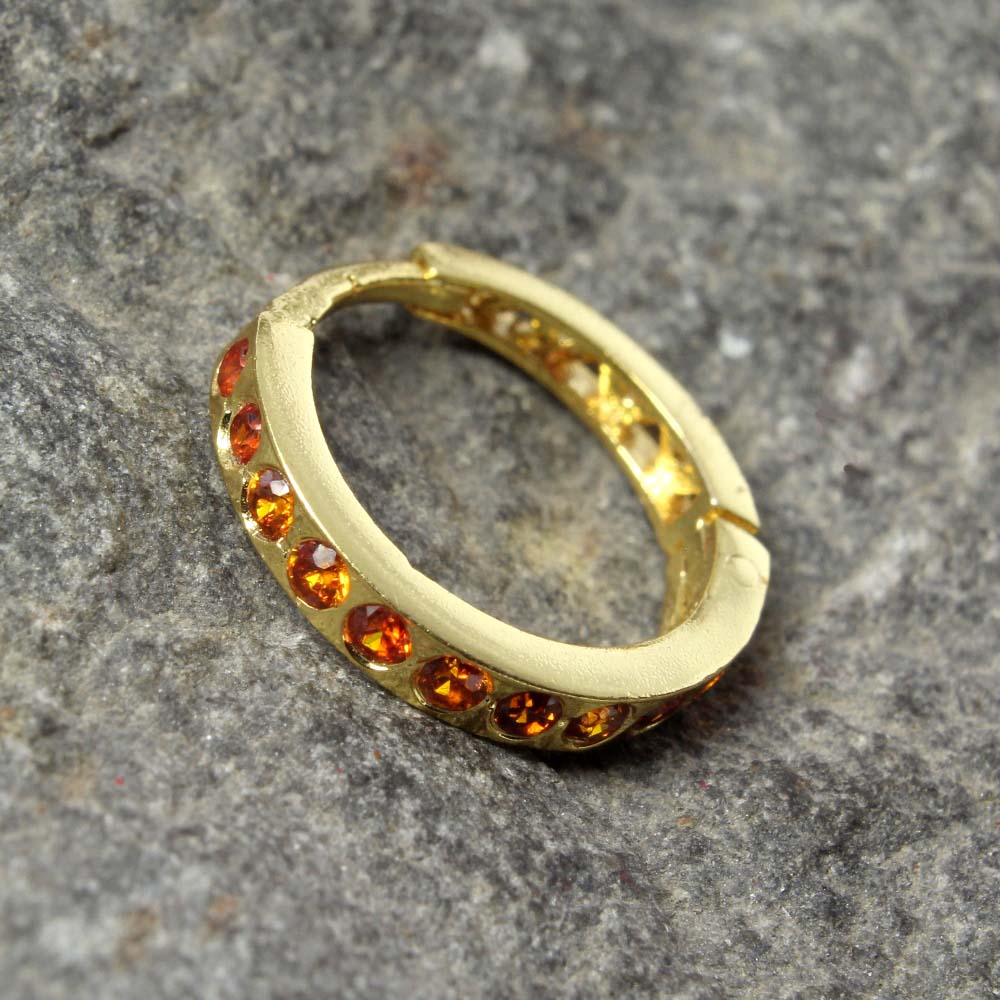 golden polished clicker nostril piercing rings made with hands and orange stones are used in making