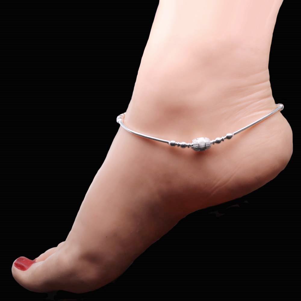 Girl wearing silver ankle chain in foot. 