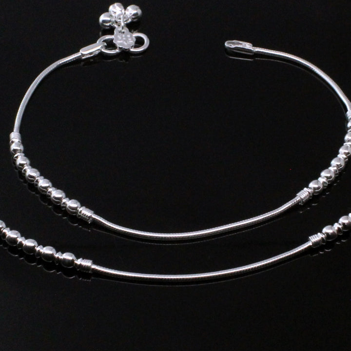 Ankle bracelet from India in sterling silver on a black background.