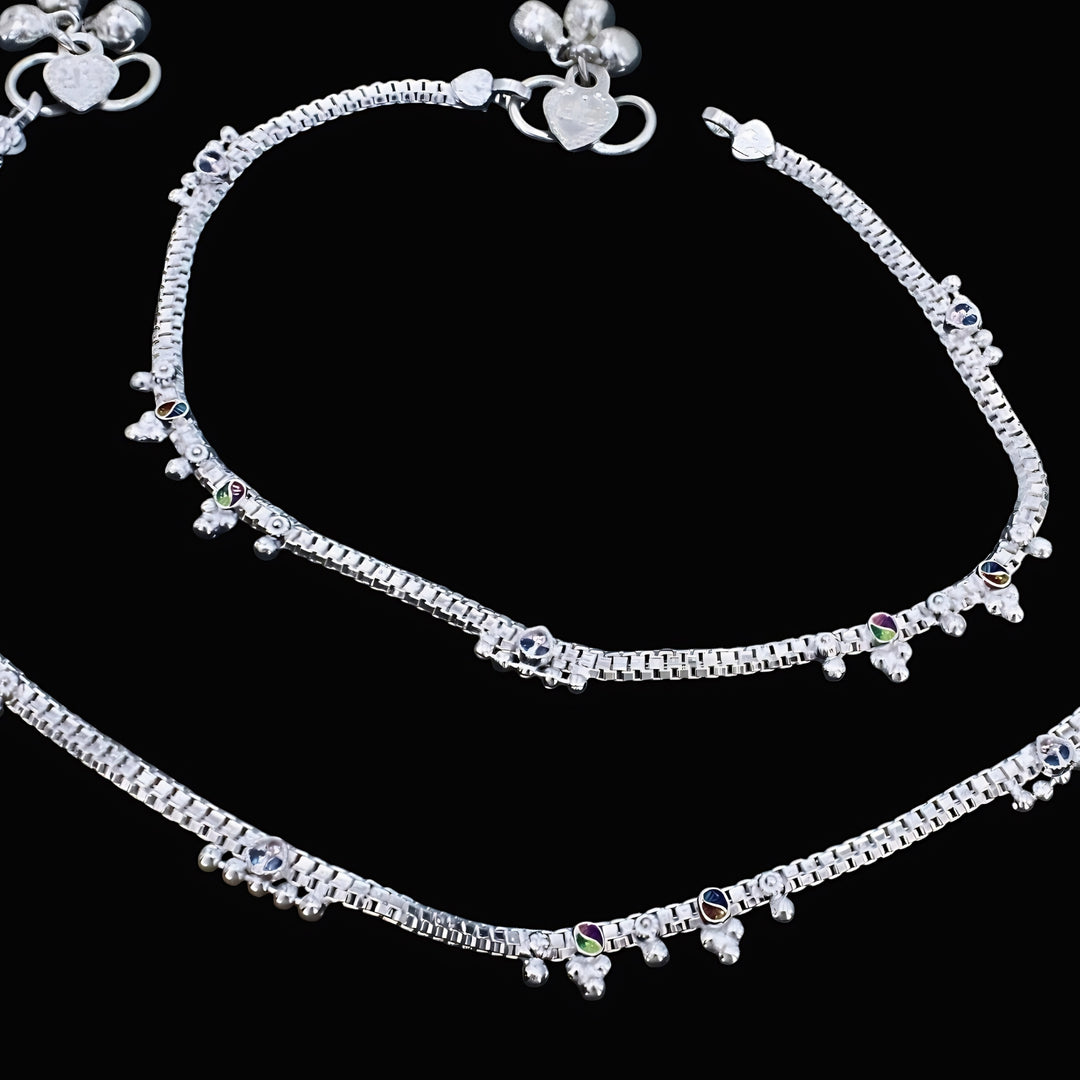 Real silver anklets adorned with ghungroo beads and colorful accents on a black background.