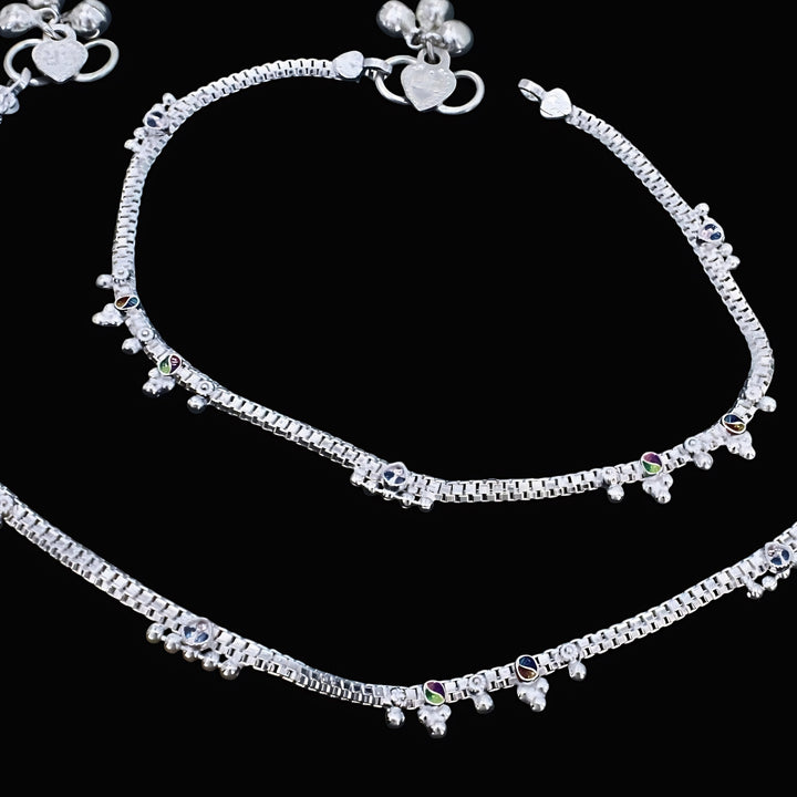 Real silver anklets adorned with ghungroo beads and colorful accents on a black background.