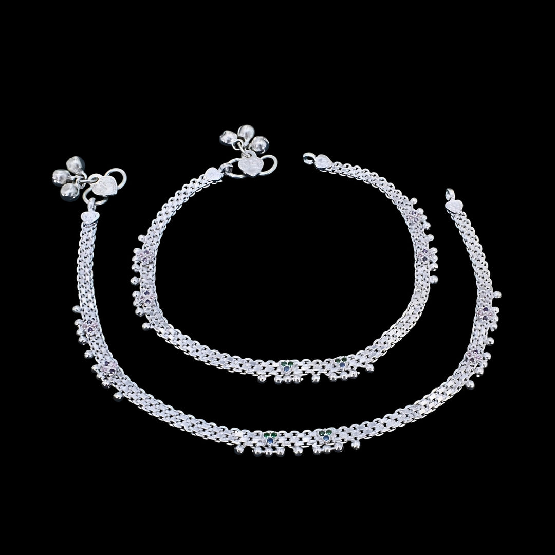 A pair of silver anklets, also known as payal, displayed against a solid black background.