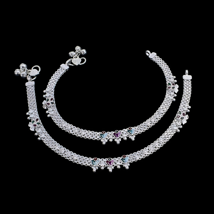 A pair of traditional silver anklets placed against a plain black background.