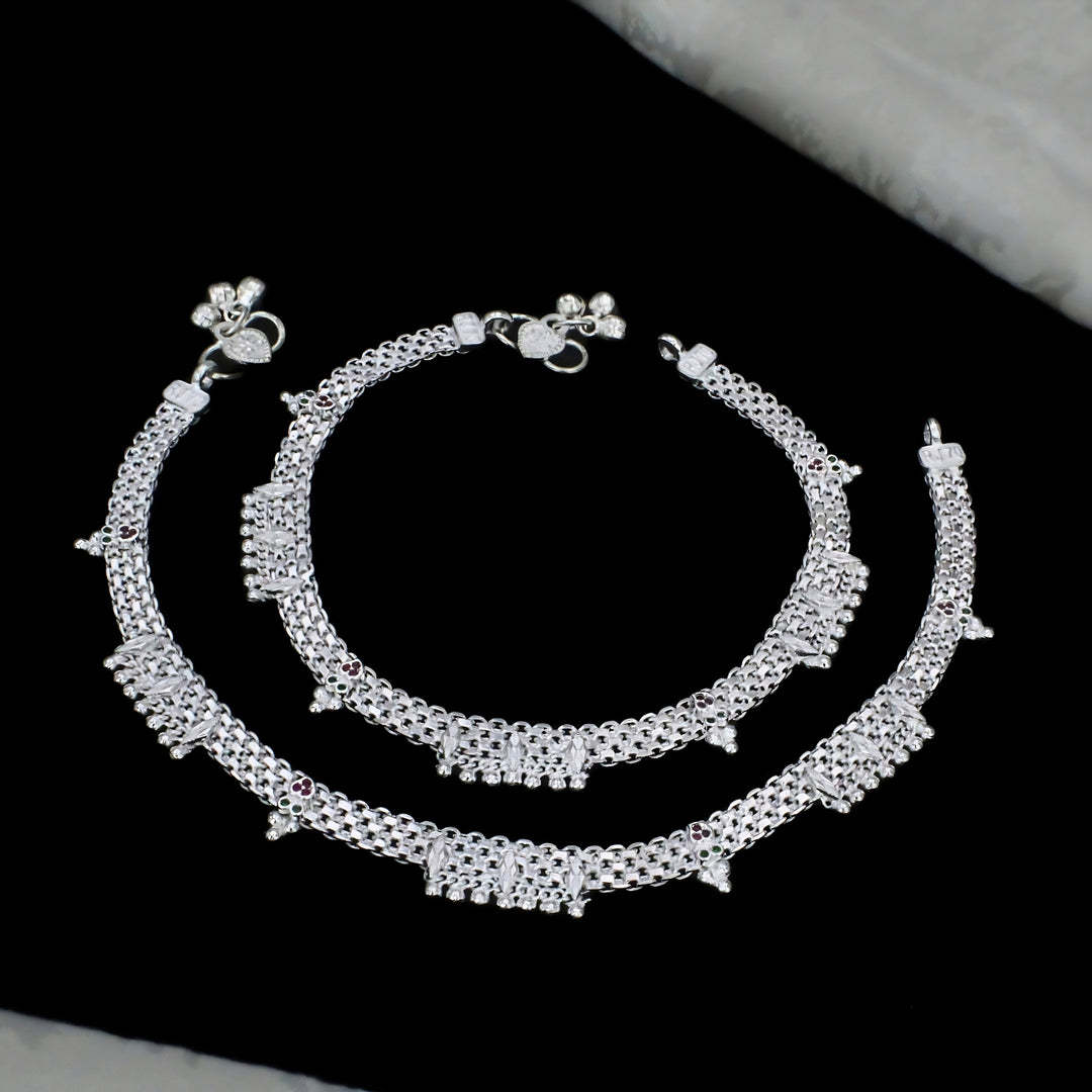 A pair of elegant silver broad-chain anklets featuring sparkling stone embellishments, colorful accents, and delicate hanging charms for a graceful traditional look.