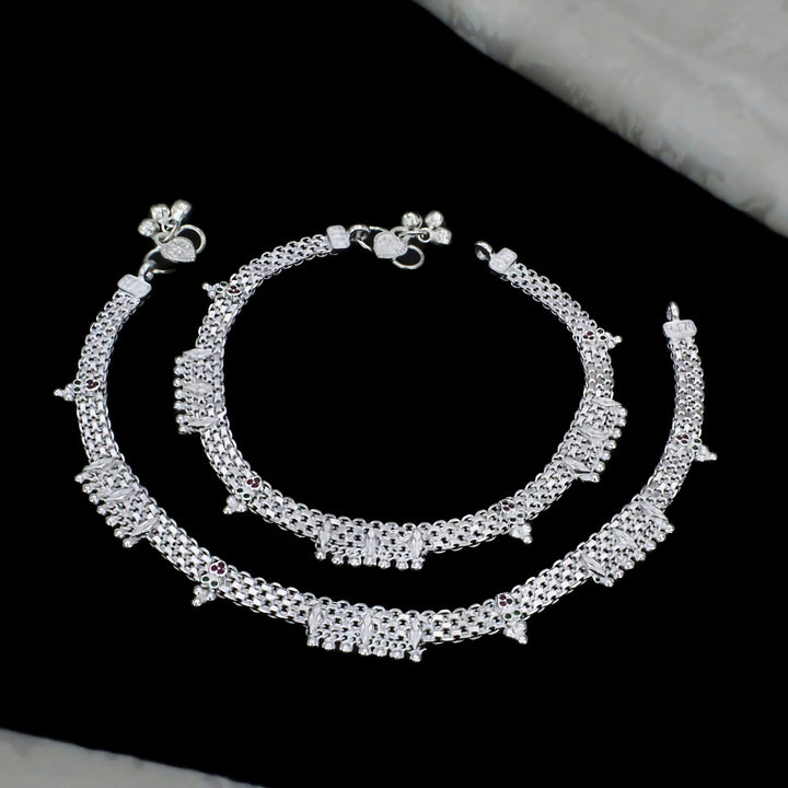 A pair of elegant silver broad-chain anklets featuring sparkling stone embellishments, colorful accents, and delicate hanging charms for a graceful traditional look.