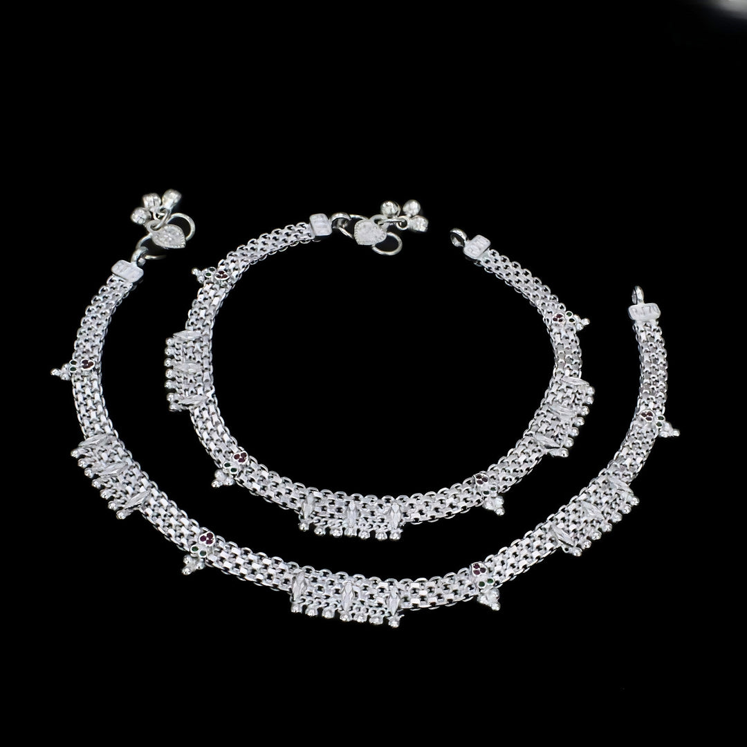 A pair of intricate silver anklets, known as payal, displayed against a solid black background.