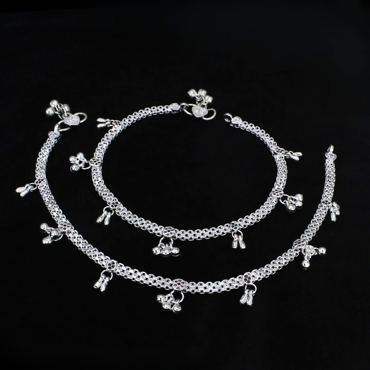 A pair of silver Indian anklets, known as payal, displayed against a solid black background.