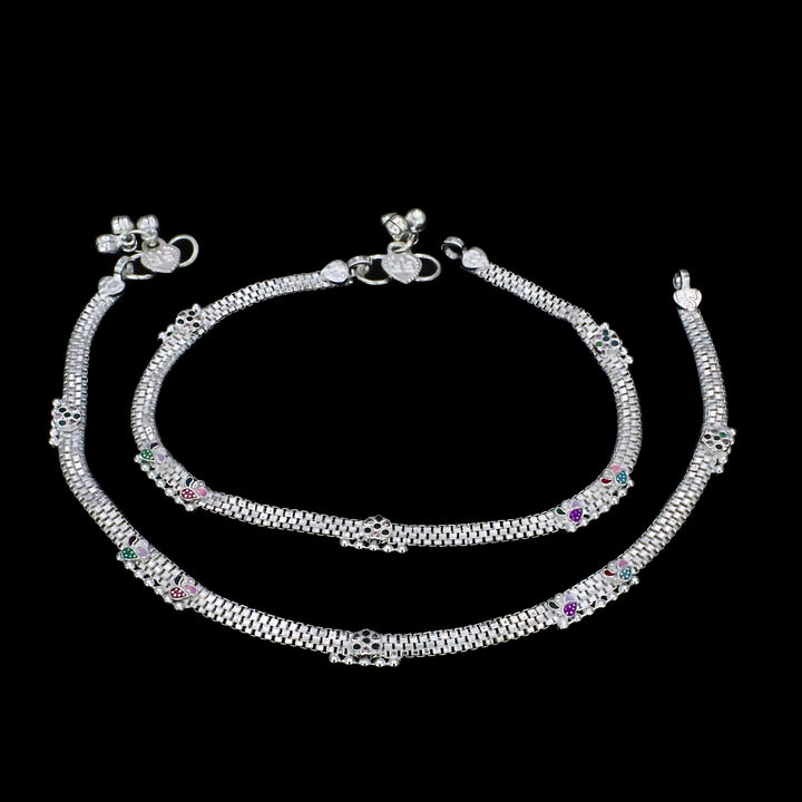 An overview of the image shows a pair of silver anklets displayed on a solid black background.