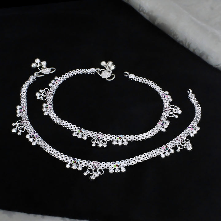 This image shows a pair of traditional silver anklets, also known as payal, displayed against a dark black fabric background.