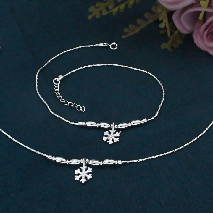 Elegant silver necklace and bracelet set featuring delicate bead accents and a sparkling snowflake charm for a timeless, graceful look.